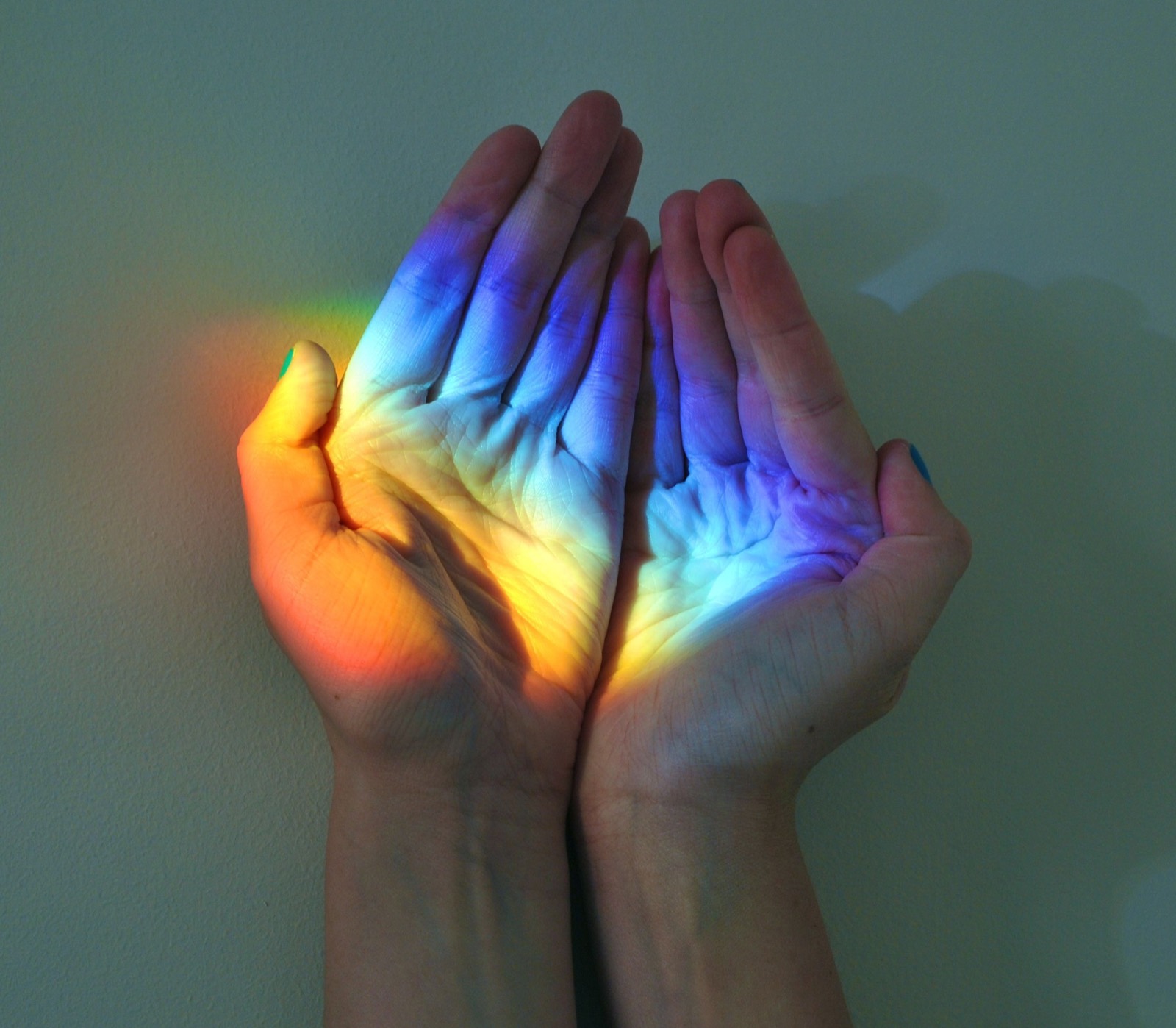 Mains éclairées par les couleurs de l'arc-en-ciel
